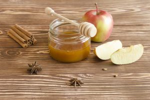 Honey jar, honey stick with slices of apples, spice on a wooden background. Rosh Hashanah (jewish holiday) concept.